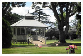 A white Victorian rotunda surrounded by open lawns and tall trees at Drayton Cemetery